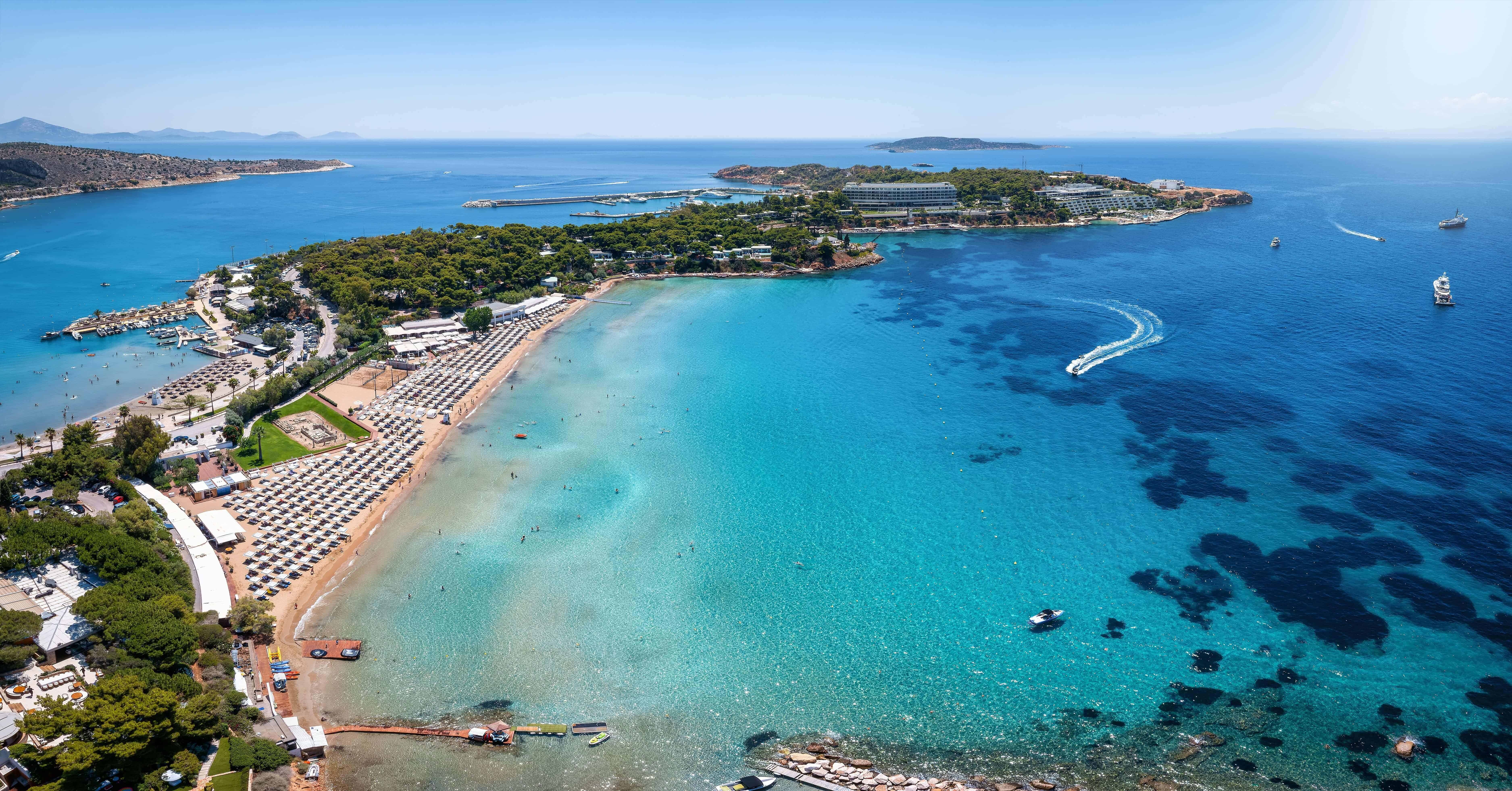 Aerial view of the famous luxury beach Astir in south Athens, bay of Vouliagmeni, Greece, with water sports over turquoise sea